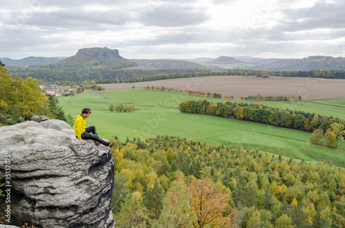 Deutschland, Sachsen, Sächsische Schweiz, Wanderung von Wehlen über die Rauensteine, Wanderer sitzt am Felsen über dem Abhang, Blick von den Rauensteinen auf den Lilienstein