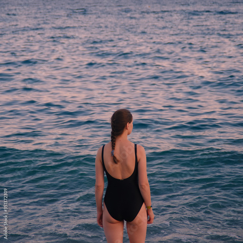 girl in a black swimsuit with her back to the sea