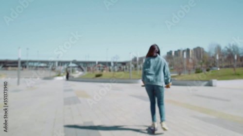 Back view of young asian woman in a jeans jacket rides a scooter in summer park photo