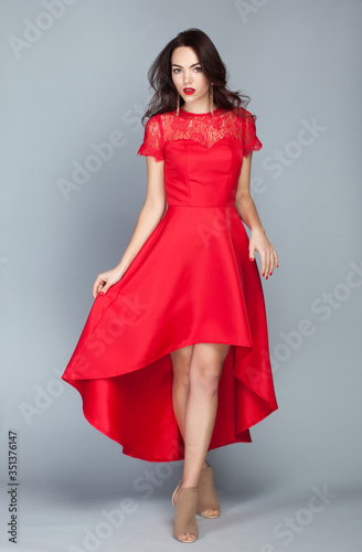 Portrait of beautiful young european brunette girl in luxury red dress on clear background