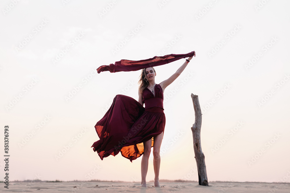 Silhouette of a girl in a red dress at sunset in the desert 