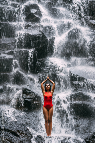 A woman does yoga at a waterfall. Healthy lifestyle. The concentration of the body. A woman does yoga in Bali. A woman meditates in nature. Meditation at the waterfall. Young woman practicing yoga