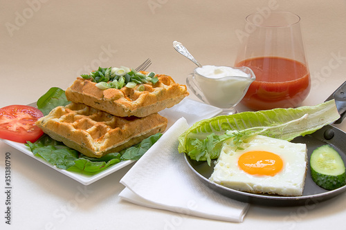 A rich breakfast of eggs with vegetables and lush waffles with cheese and greens