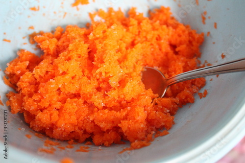 fresh carrots grated in a blue bowl
