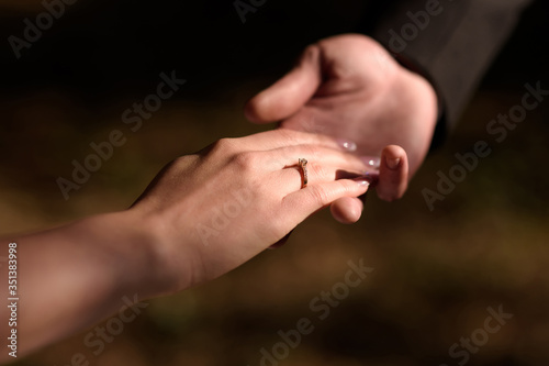 Man holds a woman's hand with a wedding ring or engagement ring on his finger. Close-up of hands.