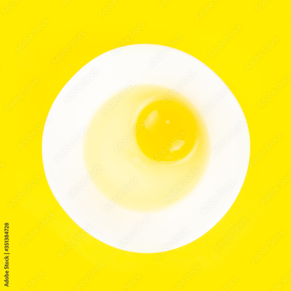 Raw egg in bowl isolated on yellow background. Healthy food and cooking at home concept. Raw egg in bowl isolated on yellow background. Healthy food and cooking at home concept.