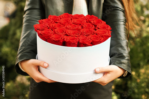 фотографія Young girl holding red roses in white gift box