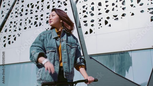 Young asian woman in a jeans jacket with the scooter waving had to her friends photo