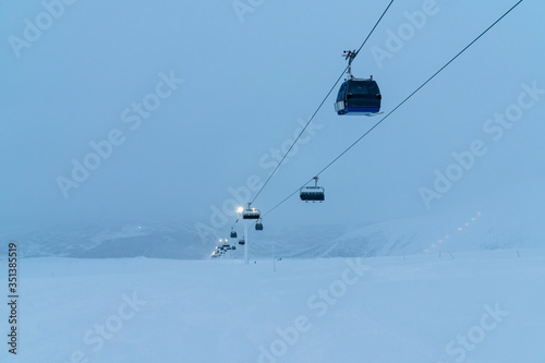 People on ski lift in winter resort - Holidays, snow gear renting, skiing, snowboarding and mountain landscape concept - Focus on guys sitting in cable car