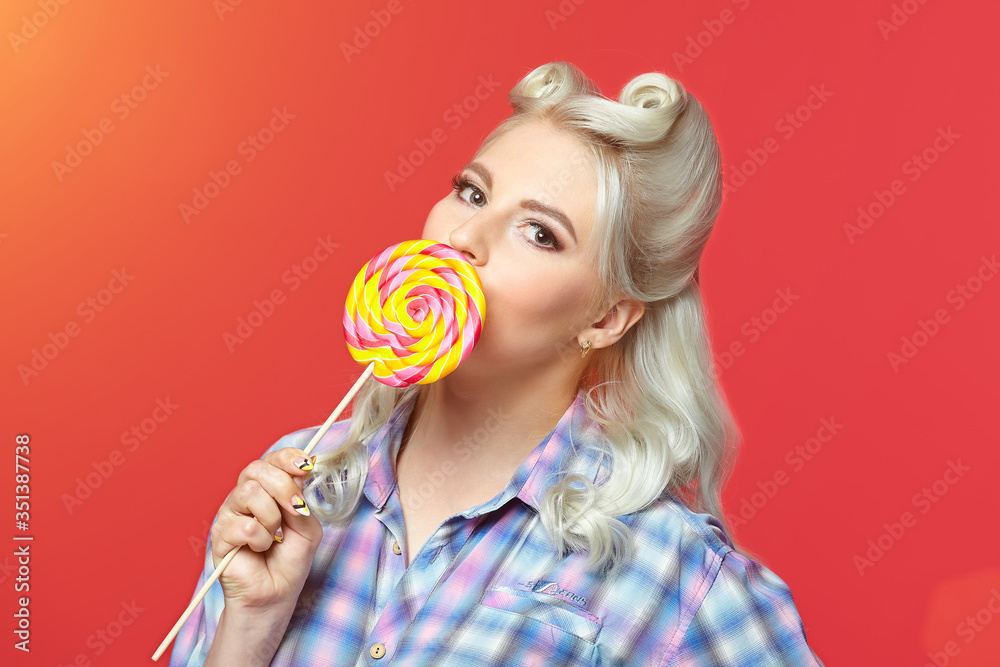 beautiful blonde with a big candy, posing on a red background