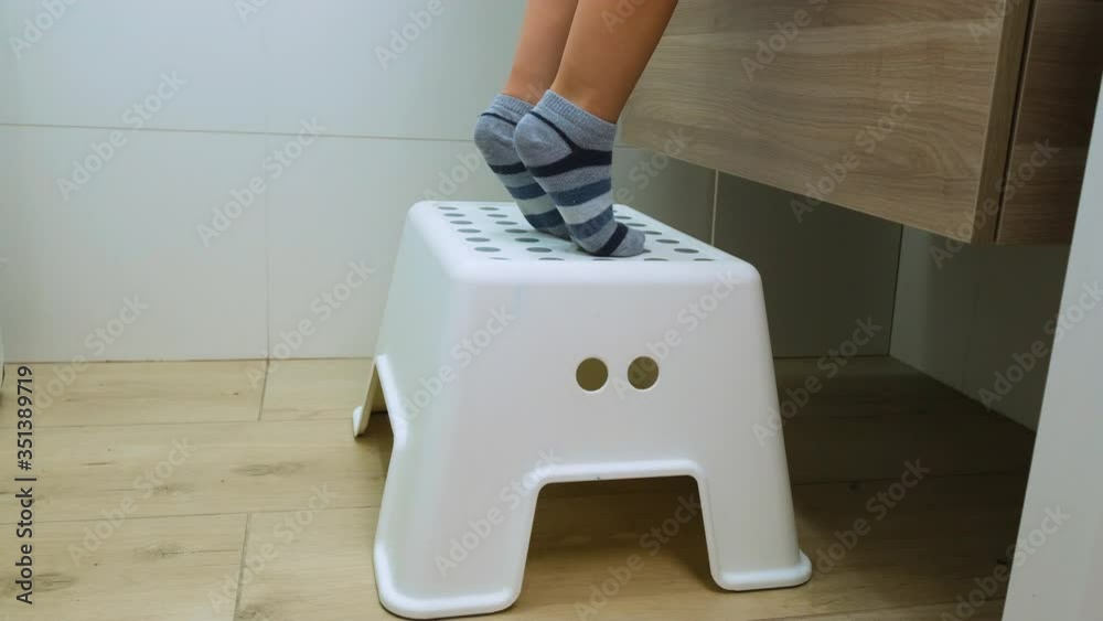 Boy enters the bathroom at the house, gets up on a chair. Cose-up of ...