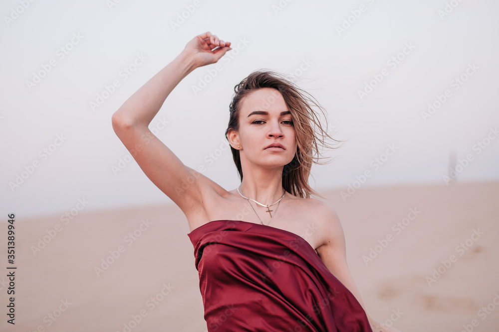 Girl with red cloth in the sunset rays in the desert Girl with red cloth in the sunset rays in the desert
