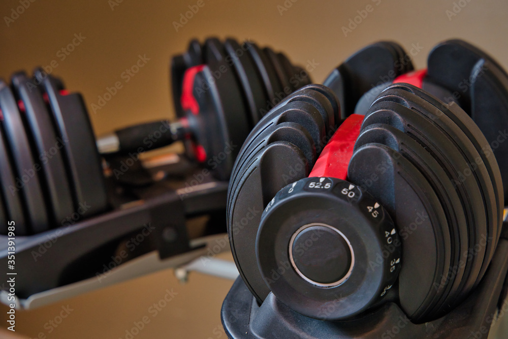 Set of adjustable dumbbells isolated on tan and brown background. Weights for working out at home. Set of adjustable dumbbells isolated on tan and brown background. Weights for working out at home.