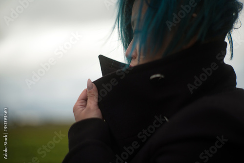 Profile of woman deep in thought with very cool short blue hair looking out into the distance 
