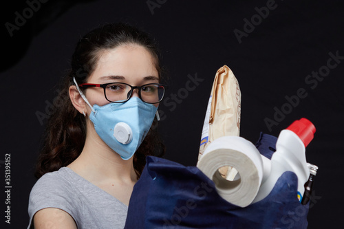 Young woman in a valve of the respiratory protective mask with a bag full of groceries from the supermarket. concept covidiots photo