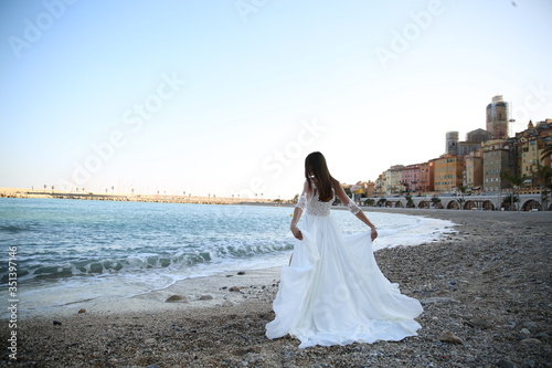 The bride in a wedding dress holds hands near the sea in Monaco.
