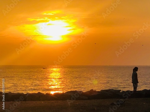 silhouette of a man walking on the beach at sunset