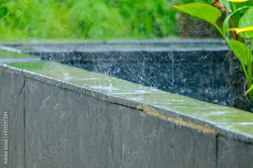 Selective focus picture of motion blur rain hitting at the side of fish pool.