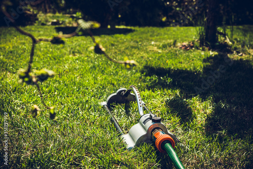 Sprinkler grass irrigation. Soil irrigation with water in the garden, the concept of care for the beauty of the garden, allotment season. Gardener cares for proper moisturizing of the soil.