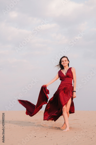 Girl in red dress at sunset in the desert