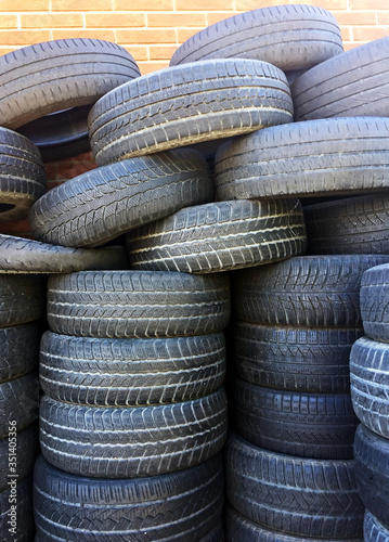 Pile of used car tires against brick wall