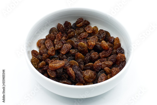 Dried raisins in a white bowl isolated on white background