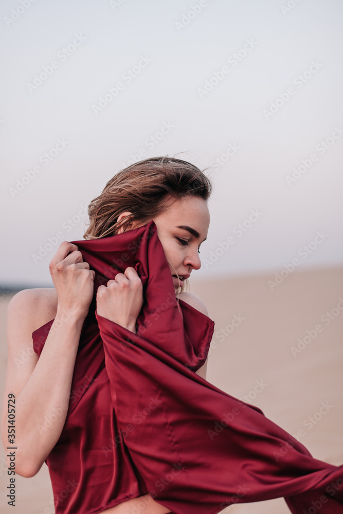 Girl with red cloth in the sunset rays in the desert Girl with red cloth in the sunset rays in the desert