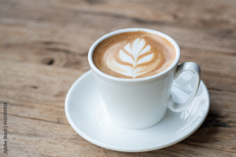 Cup of hot coffee with milk art on the surface placed on the wooden table Cup of hot coffee with milk art on the surface placed on the wooden table