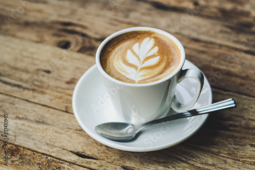 Cup of hot coffee with milk art on the surface placed on the wooden table