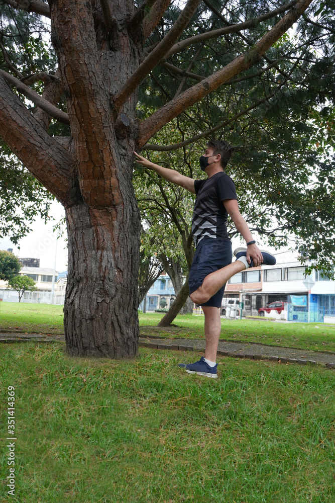 white man doing stretching exercises in the park outdoors wearing mask white man doing stretching exercises in the park outdoors wearing mask
