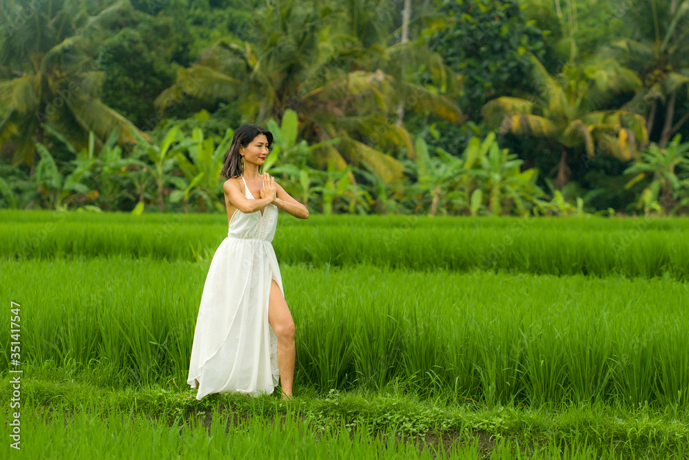 body and mind connection with nature - happy and beautiful Asian Korean woman doing yoga and meditation exercise outdoors at idyllic green rice field enjoying tropical holidays body and mind connection with nature - happy and beautiful Asian Korean woman doing yoga and meditation exercise outdoors at idyllic green rice field enjoying tropical holidays