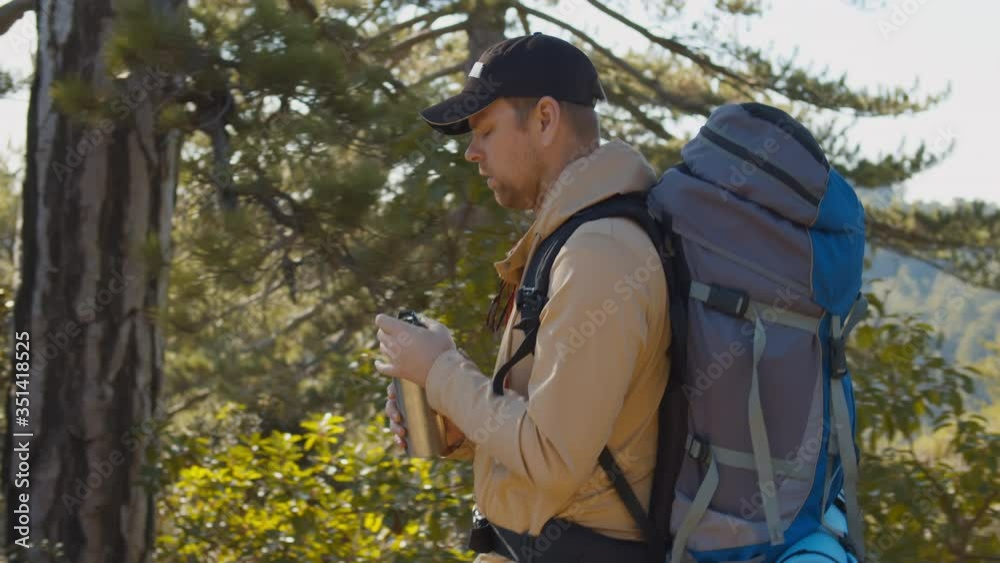 Backpacker male going by the path through pine forest Backpacker male going by the path through pine forest