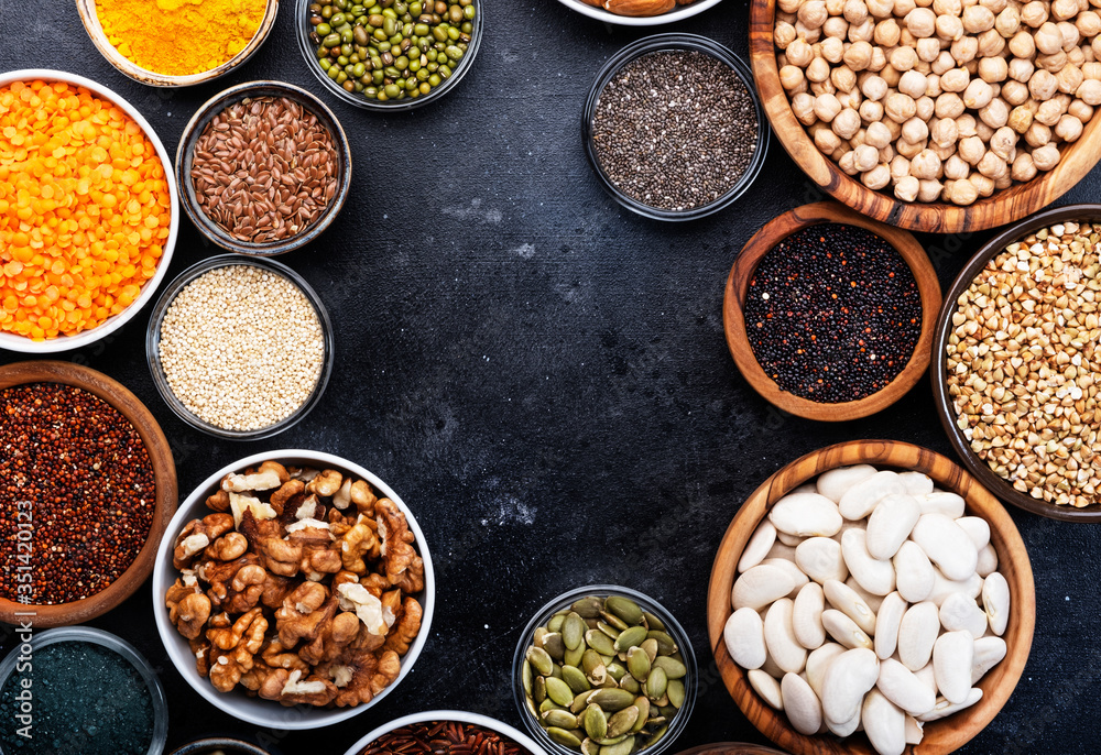 Fototapeta Superfoods, legumes, nuts, seeds and cereals selection in bowls on grey background. Superfood as chia, spirulina, beans, goji berries, quinoa, turmeric, mung bean, buckwheat, lentils, flax seed