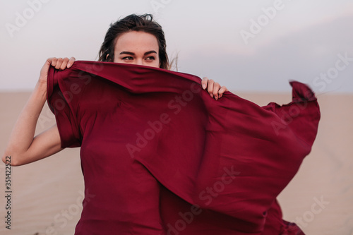 Girl with red cloth sits on the sand