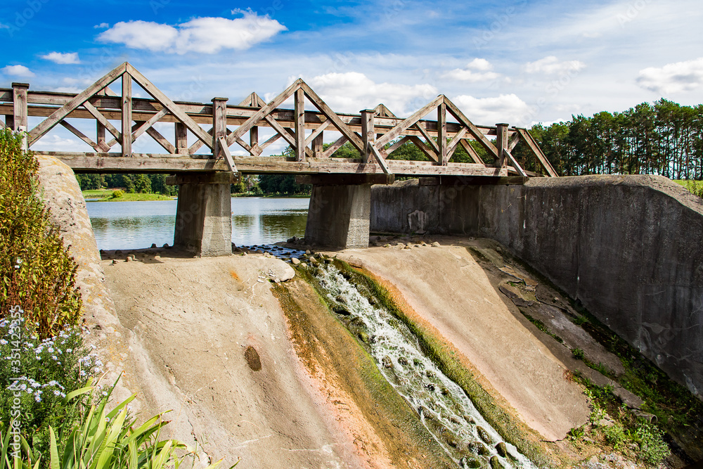 Old dam with a wooden bridge. View of the summer  landscape.