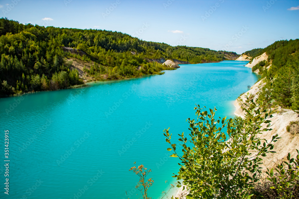 Beautiful mountain landscape - a lake with unusual turquoise water in the crater. Chalk quarry in Belarus.