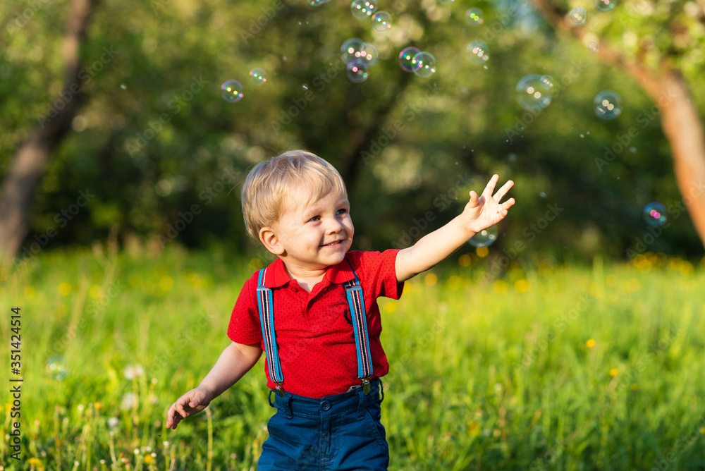 child boy has fun playing in nature with shiny soap bubbles child boy has fun playing in nature with shiny soap bubbles