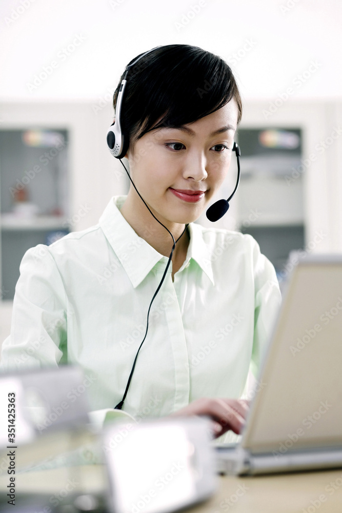 Businesswoman using laptop and microphone headset Businesswoman using laptop and microphone headset