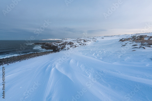 Fototapeta Naklejka Na Ścianę i Meble -  Waves break on the Gulf coast against the backdrop of snow-capped mountains of the Arctic 