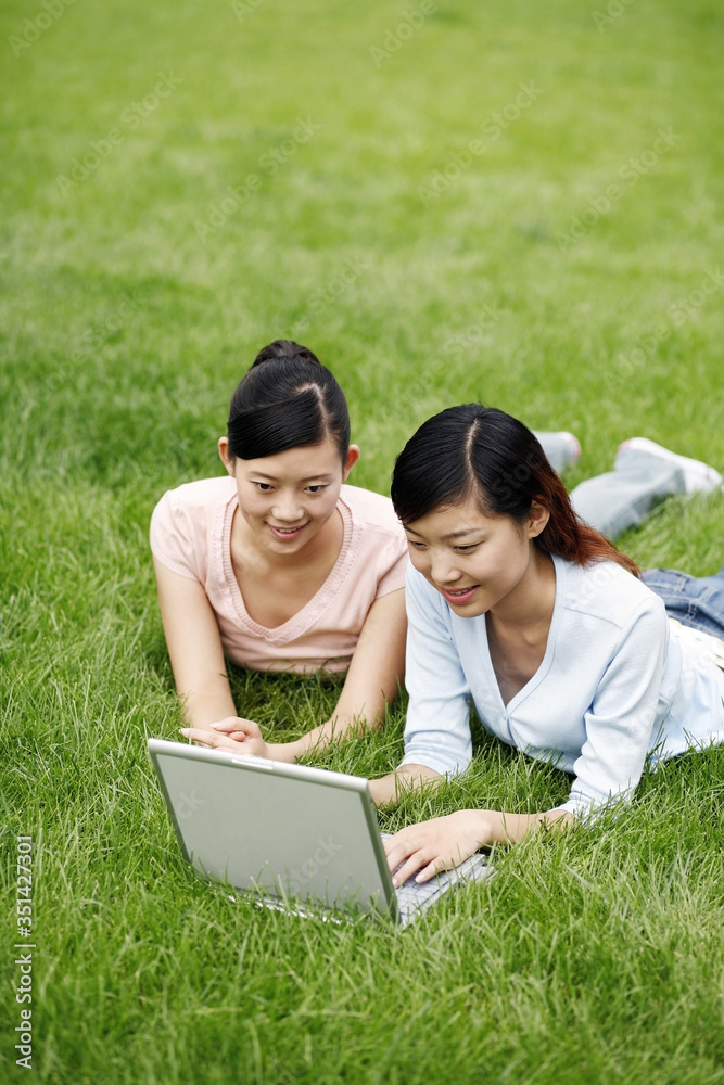 Students lying on field using laptop Students lying on field using laptop
