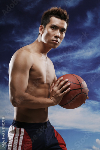 Man holding basketball while looking at camera © ImageHit