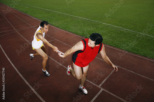 Man passing baton to his teammate in a relay event