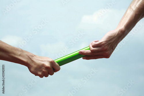 Two men's hands passing the baton in a relay race photo