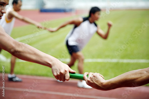 Man passing baton to his teammate in a relay event