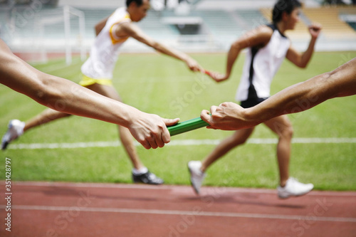 Man passing baton to his teammate in a relay event