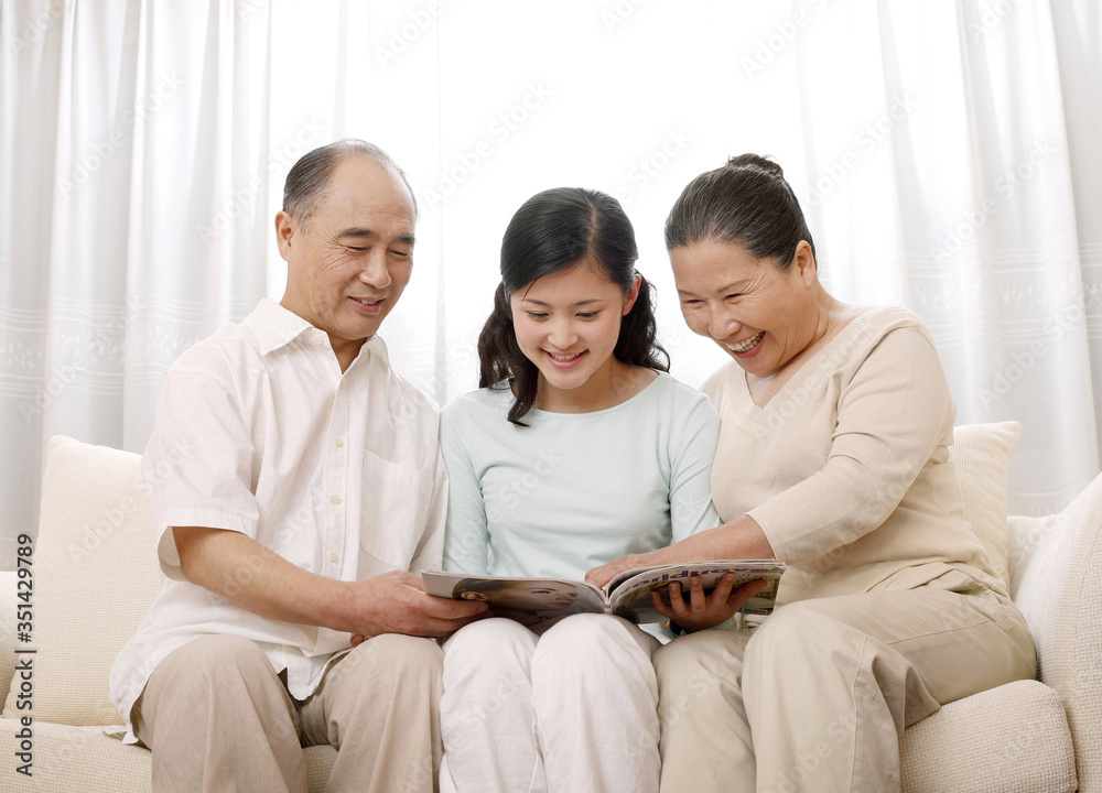 Woman reading magazine with senior man and woman Woman reading magazine with senior man and woman