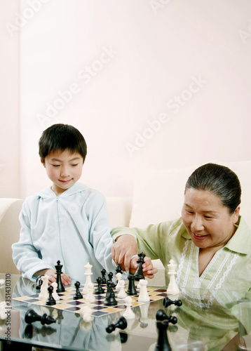 Senior woman and boy playing chess game
