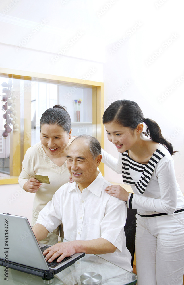 Senior man and woman using laptop for online banking, woman watching Senior man and woman using laptop for online banking, woman watching