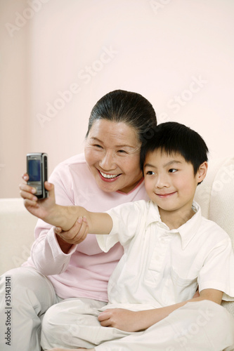 Senior woman and boy taking picture with camera phone