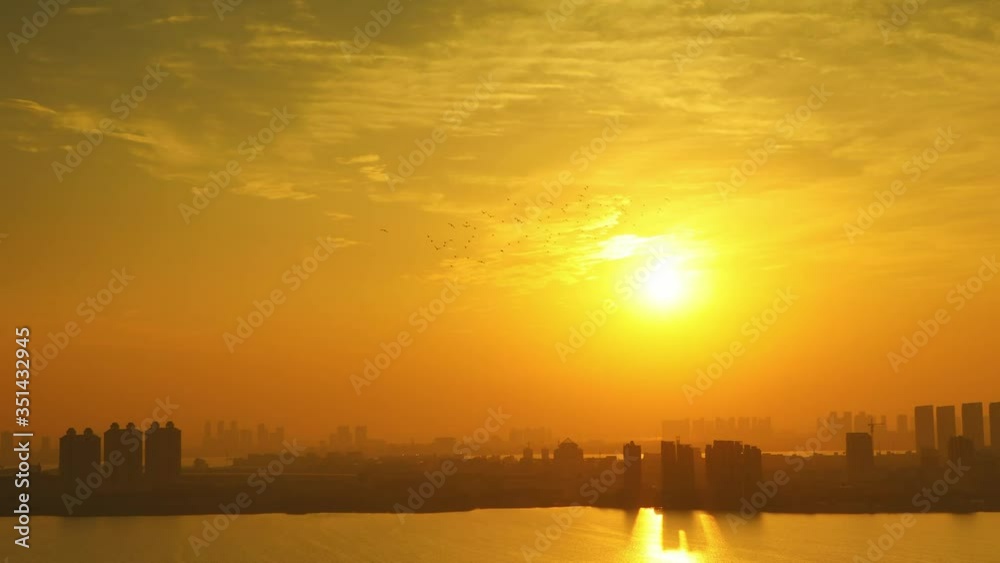 Cityscape at sunset: a flock of birds flies across the sky Cityscape at sunset: a flock of birds flies across the sky